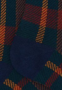 Calze a maglia con un motivo scozzese in verde scuro, rosso e giallo, con il tallone blu navy. La texture è liscia con dettagli a coste.
