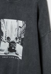 Sweat-shirt gris foncé avec un graphisme d'un bouledogue français dans une rue de la ville, accompagné du texte "GARDER LA VIE SIMPLE" en bas.