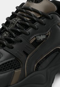 Černá a hnědá teniska z mřížkového a syntetického materiálu, s propracovaným šněrováním, polstrovaným lemováním a značkovým logem na boku.