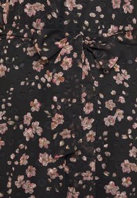 Schwarzer Stoff mit floralem Muster in Pink- und Goldtönen. Enthält einen Stoffgürtel in der Taille und strukturierte, kreisförmige Details.