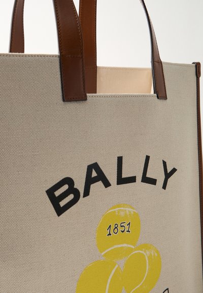 Μπεζ καμβάς τσάντα ώμου με καφέ δερμάτινες λαβές, με μαύρο κείμενο "BALLY" και κίτρινες γραφικές παραστάσεις τεννιστικής μπάλας με τη λεπτομέρεια "1851".