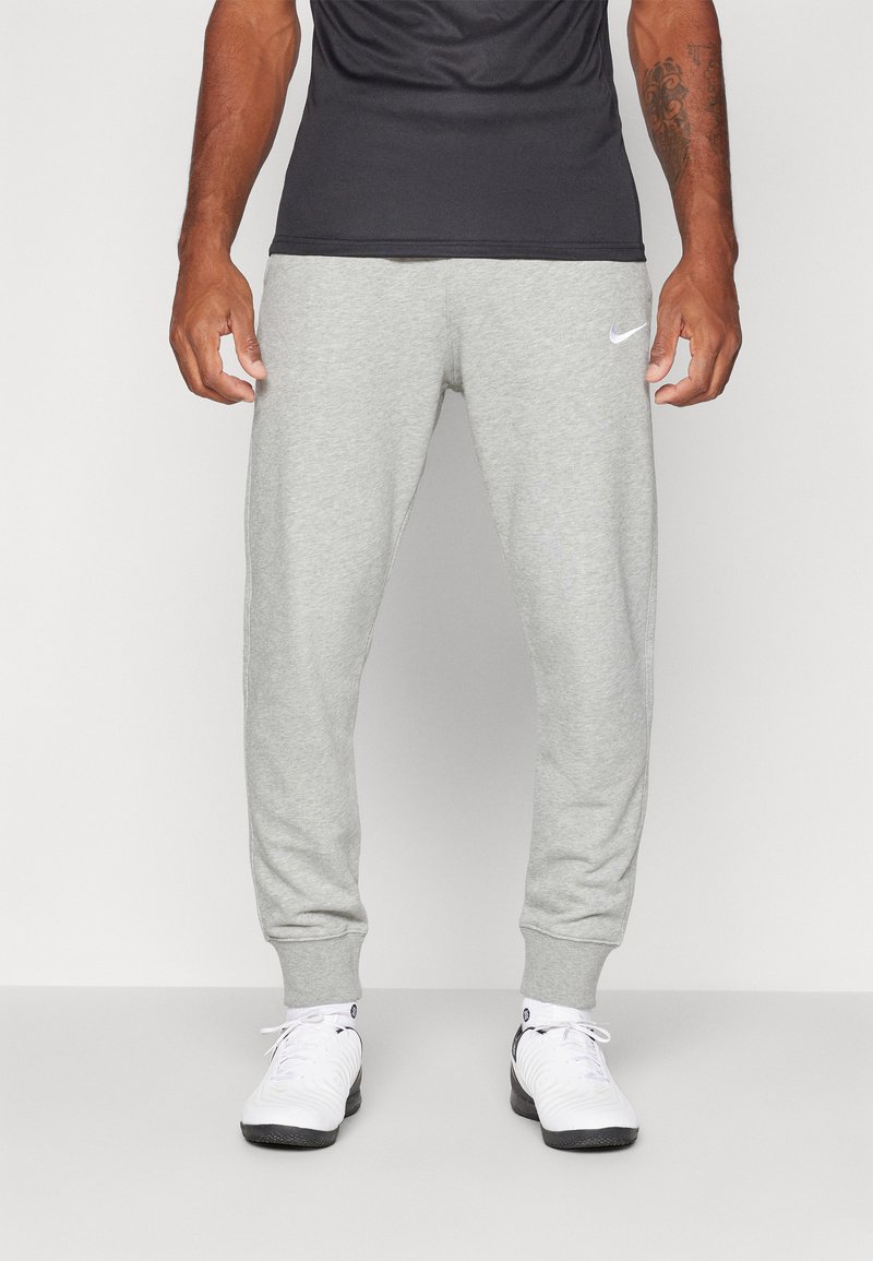 Pantaloni in cotone grigio con un design affusolato, polsini elastici e un piccolo logo Nike bianco sul lato sinistro. Indossati con sneaker bianche.