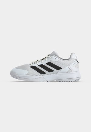 Chaussure de sport Adidas blanche basse avec design à trois bandes noires, fermeture à lacets à l'avant et semelle texturée pour une bonne adhérence.