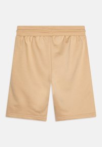 Beigefärgade shorts i mjukt tyg med elastisk midja, raka ben och minimala sömdetaljer. Inga fickor eller mönster.