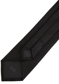 Svart vävd slipset med en slät textur, som har en solid svart accentsektion och en subtil logo i änden.