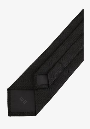 Mustmust mustriibul, millel on sile tekstuur, musta aktsentosa ja diskreetne logo otsas.