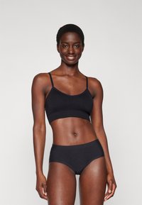 Black bra and matching brief set made from soft, stretchy material. The bra features thin straps and a seamless design.