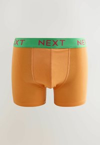 Oranžinės elastingos medžiagos apatinės kelnaitės su žaliu diržu, turinčios raudoną "NEXT" logotipą ir sklandžią tekstūrą, skirtos patogumui ir pritaikymui.