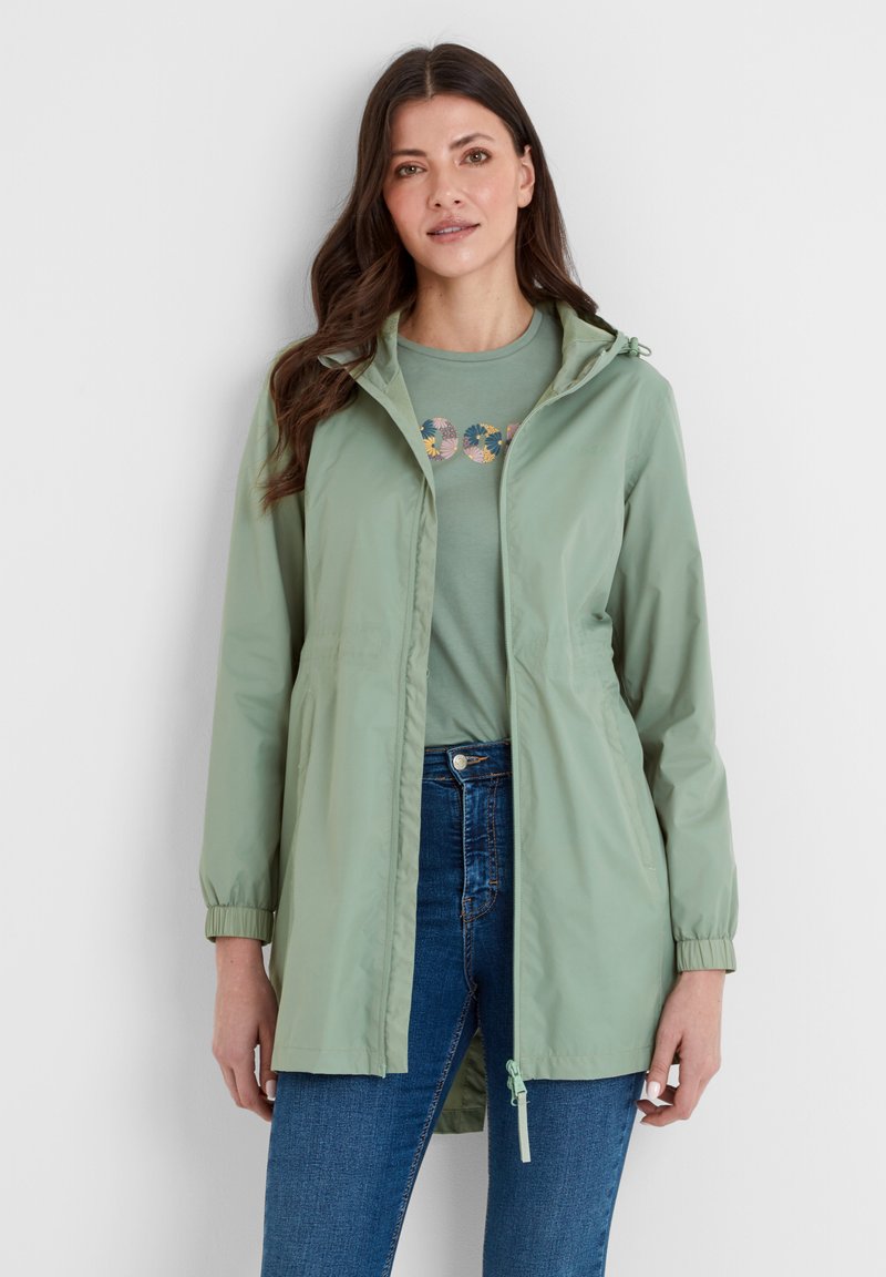 Light green waterproof jacket with a hood, elastic cuffs, and drawstring hem, worn over a matching t-shirt and blue jeans. Smooth texture.