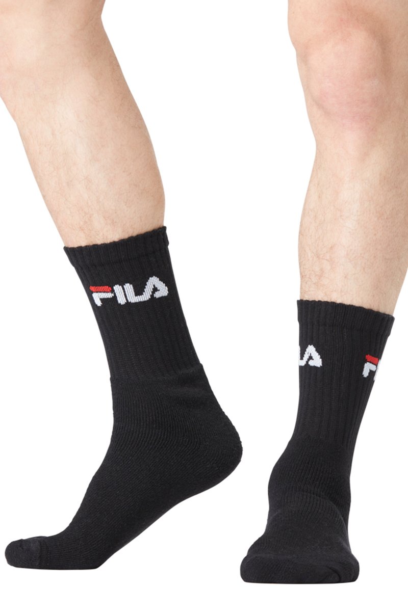 Chaussettes noires côtelées avec le logo "Fila" blanc et rouge. Matériau extensible, longueur mi-mollet, avec une couleur unie et un design classique.