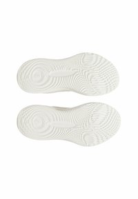 Semelles de chaussures de sport blanches avec des motifs texturés, comportant des designs circulaires et ondulés. Matériau léger, logo minimal visible.