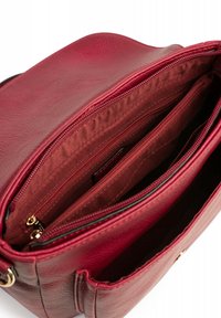 Rode leren handtas met een gestructureerd oppervlak, meerdere met rits afgesloten vakken en een zacht stoffen interieur. Gouden hardware accenten zichtbaar.