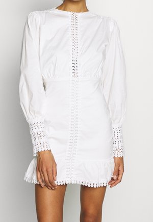 Weißes Mini-Kleid mit langen Ärmeln und Spitzenbesatz in der Mitte, an den Manschetten und am Saum, mit geraffter Taille und leichtem Rüschensaum.