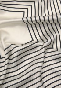 Saténová látka s krémovým pozadím a výraznými černými vodorovnými a obdélníkovými pruhy, vytvářející hladký a texturovaný vzhled.