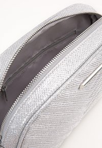 Clutch bag con texture argentata con chiusura a zip, presenta un interno grigio liscio e un sottile accento metallico lucido sul fronte.