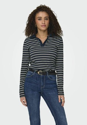 Marinrandig långärmad polo med v-ringning och kontrasterande krage, parat med högmidjade blå jeans och ett svart bälte.