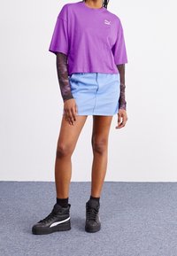 Fialový krátký tričko, světle modrá džínsová sukně a černé vysoké tenisky s bílými akcenty. Krátké rukávy a uvolněný střih.