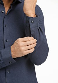 Marinblå knapp-up skjorta gjord av texturerat tyg med långa ärmar, med en enda knappmanschett och en prydligt skräddarsydd passform.