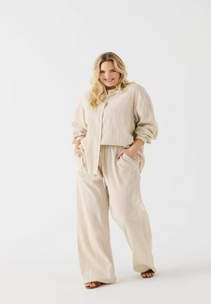 Beige two-piece outfit featuring a short-sleeved, button-up top and wide-leg pants, both in textured fabric with side pockets.