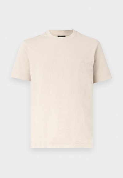 Μπεζ κοντομάνικο T-shirt με στρογγυλή λαιμόκοψη και διακριτικό ανάγλυφο λογότυπο στο αριστερό στήθος, παρουσιασμένο σε απλό λευκό φόντο.