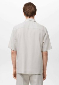 Korte mouwen shirt in lichtgrijze stof, met een eenvoudige kraag, rechte snit en subtiele stiksels op de achterkant.