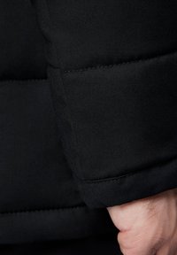 Czarna kurtka puchowa z gładkiego, teksturowanego materiału. Posiada wyściełane rękawy z kontrastowym przeszyciem oraz dopasowaną krawędź mankietu.