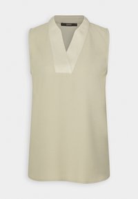 Blouse beige sans manches avec un col en V et un liseré clair contrastant au niveau du col, en tissu lisse.