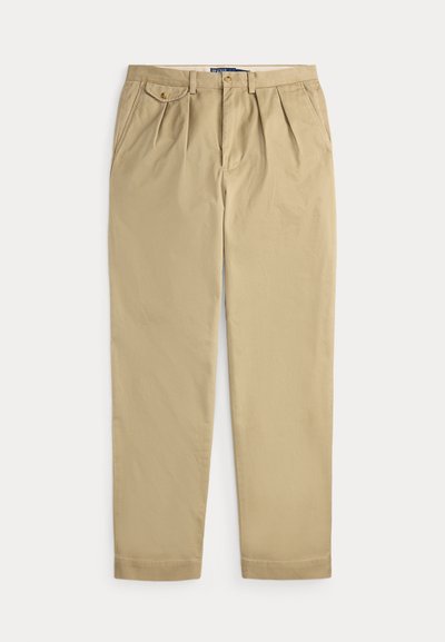 Beige geplooide broek met zijzakken, een klein knoopsluitbaar muntzakje aan de rechterkant, riemlussen en een voorste knoop- en ritssluiting.