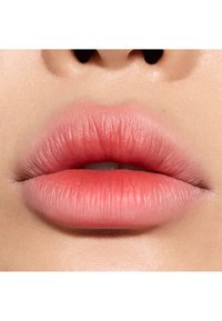 Maquillage des lèvres présentant un dégradé du rose doux au corail, avec une texture lisse et une finition naturelle. Lignes fines visibles sur les lèvres.