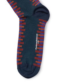 Calcetines con base azul oscuro y acentos de patrones geométricos en rojo, naranja y púrpura; textura de punto con un logo cerca del puño.