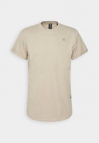 T-shirt beige à manches courtes col rond avec petit logo sur la poitrine gauche et étiquette latérale, présenté sur un fond blanc uni.