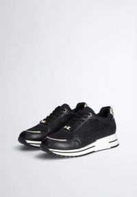 Schwarze Sneakers mit Netzdetails, glatten Lederakzenten, einer weiß-schwarzen strukturierten Sohle und metallischen Beschlägen an den Schnürsenkeln.