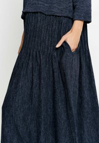 Mörkblå plisserad midiklänning tillverkad av textil, med en avslappnad passform och sidfickor, rund halsringning och långa ärmar.