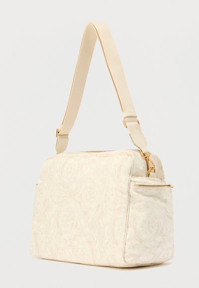 Μπεζ τσάντα με λουλουδάτο μοτίβο και επενδεδυμένη υφή, διαθέτει αποσπώμενο λουρί και χρυσά μεταλλικά στοιχεία, διπλό φερμουάρ και πλαϊνή τσέπη.