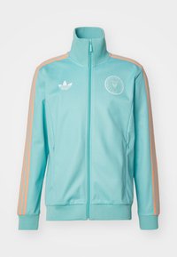 Lysblå sporty zip-up jakke med orange striber og ribbede manchetter. Har et logo på brystet og sidelommer.