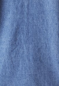 Denimstoff in mittelblauer Farbe mit glatter Textur und subtilen Schattierungsvariationen, die ein leicht zerknittertes Erscheinungsbild zeigen.
