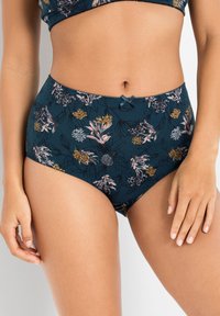 Costume da bagno floreale a vita alta in teal con fiori a fantasia in rosa e giallo. Ha un bordo in pizzo e un piccolo fiocco decorativo in vita.