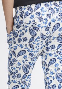 Blauw en witte broek met een paisleypatroon van bladeren en bloemen. Elastische tailleband en zijzakken. Katoenen stof.