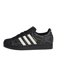 Black leather sneaker with white star patterns, three white stripes on the side, and a rubber toe cap. Lace-up design with a textured sole.