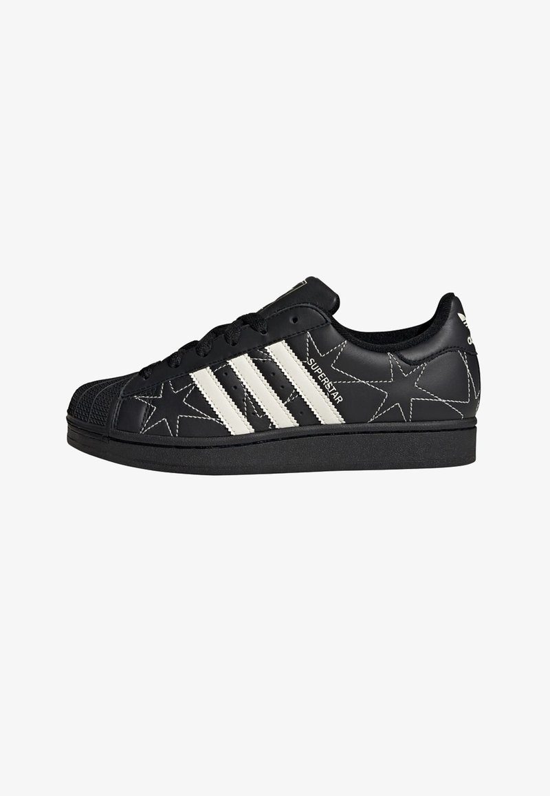 Black leather sneaker with white star patterns, three white stripes on the side, and a rubber toe cap. Lace-up design with a textured sole.