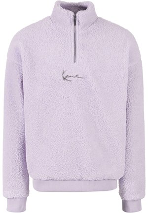Vaaleanliila fleece-pullover, jossa on korkea kaulus, puoli-vetoketju ja brodeeraus rintaosassa. Varustettu ribbatuilla hihoilla ja helmalla.