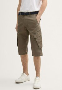 Khaki cargo shorts med flere sidelommer, lavet af slidstærkt stof, med en lynlåslomme, og parret med et marineblåt bælte.