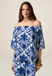 Schulterfreies Oberteil aus leichtem Stoff, mit einem blau-weißen Blumenmuster, puffärmelig und mit einem elastischen Ausschnitt.