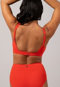 Rode bikini set met een gestructureerde stof. Het topje heeft verstelbare bandjes en een haaksluiting op de rug. De hoogwaardige onderkant maakt de look compleet.