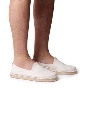 Zapatos de lona tipo slip-on en beige claro con un diseño texturizado, suela plana de esparto y detalles de cuerda de yute natural en el borde.