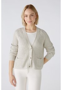 Hellgraue Strickjacke mit geripptem Muster, V-Ausschnitt, Knopfverschluss und zwei Fronttaschen. Lange Ärmel mit aufgekrempelten Bündchen.