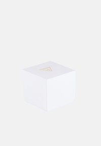 Boîte carrée blanche en matériau texturé, avec un logo de triangle doré sur le dessus. Design simple avec un couvercle qui s'ajuste parfaitement.