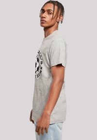 Gray cotton t-shirt featuring a circular black graphic print on the front. Short sleeves and a relaxed fit with a straight hem.