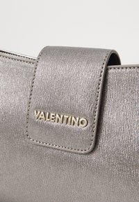 Silberner metallischer Handtasche mit texturiertem Finish. Mit einem goldenen "Valentino"-Logo auf einem Klappverschluss. Kompakte rechteckige Form.
