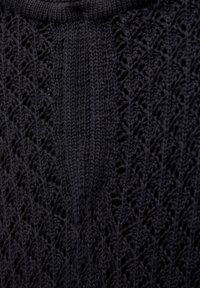 Tissu tricoté noir avec un motif texturé comportant des éléments ajourés. Le design côtelé ajoute de la dimension à l'apparence générale.
